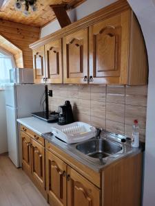 a kitchen with wooden cabinets and a sink at Henrietta Apartmanház in Zalakaros