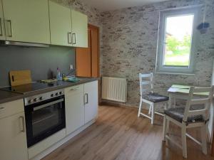a kitchen with white cabinets and a table and a window at Ferienwohnung Emil's Kuhwiese in Breitenbach