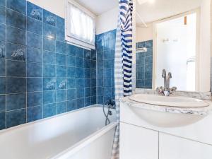 a blue tiled bathroom with a tub and a sink at Studio Hameau de Pech I-2 by Interhome in Cap d'Agde