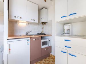 cocina con armarios blancos, fregadero y microondas en Studio Hameau de Pech I-2 by Interhome, en Cap d'Agde