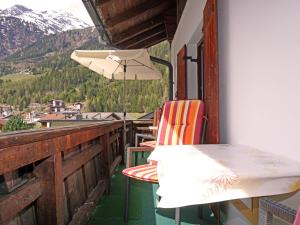 uma varanda com uma mesa, uma cadeira e um guarda-chuva em Apartment Mühlbach by Interhome em Vergötschen