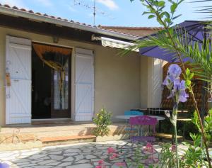 a house with white doors and a table and purple chairs at Au coeur de la Provence Verte in Le Cannet-des-Maures