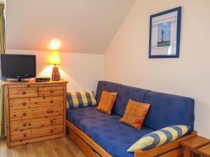 un salon avec un canapé bleu et une télévision dans l'établissement Apartment Le Bénétin - DAR303 by Interhome, à Dinard
