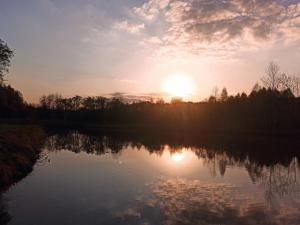 a sunset over a lake with the sun setting at Holiday Home Lgota in Witanowice