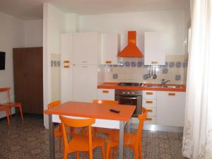 a kitchen with a wooden table and orange chairs at Apartment Bellavista-2 by Interhome in Cattolica