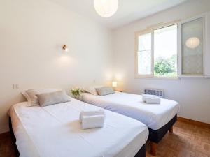 カルナックにあるVilla Trezen by Interhomeの白い壁の客室で、ベッド2台、窓が備わります。