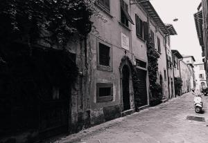 een zwart-witte foto van een scooter geparkeerd naast een gebouw bij Dimora Coccapani in Pisa