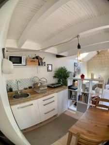 een keuken met witte kasten en een houten tafel bij Appart chic et cosy/centre ville/ 20min de Paris in Maisons-Laffitte