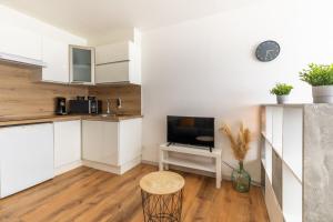 a kitchen with white cabinets and a tv and a table at La fée verte in Pontarlier