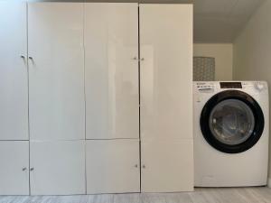 a laundry room with white cabinets and a washing machine at Homelivia, ATTIC ROOM -Mansardé sous les toits de Nice in Nice