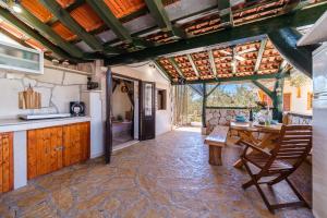 an open kitchen with a table and a wooden ceiling at Holliday Home "Maslinada" in Milna