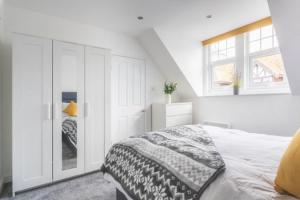 a white bedroom with a bed and a window at Coast View Luxury Apartment in Lyme Regis
