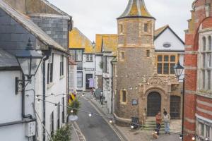 a group of people walking down a street with a tower at Coast View Luxury Apartment in Lyme Regis