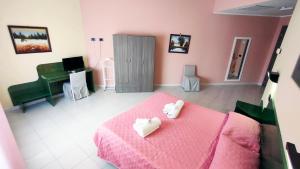 una camera con un letto rosa e due asciugamani bianchi di Hotel Mater Mediterranea a Senorbì