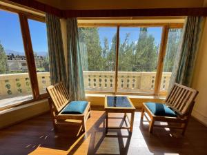 two chairs and a table in front of a large window at Hinjumaa guest house in Leh