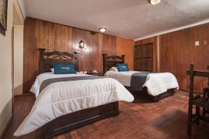 2 camas en una habitación con paredes de madera en Ayenda Casa Escondida San Cristóbal Premium, en Cusco