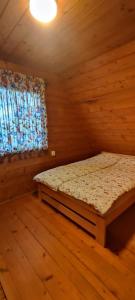 1 dormitorio con 1 cama en una habitación de madera en Dom w Czostkowie na Suwalszczyźnie, en Rospuda