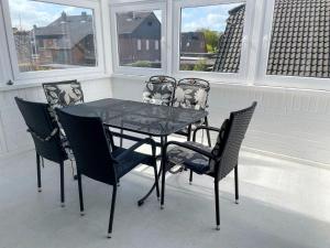 - une table et des chaises noires sur une terrasse couverte avec fenêtres dans l'établissement Apartment Seeteufel by Interhome, à Norddeich