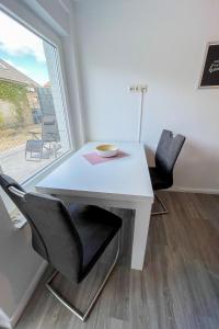 einen weißen Tisch und Stühle in einem Zimmer mit Fenster in der Unterkunft Apartment Riff by Interhome in Norddeich