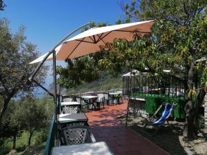 a patio with tables and chairs under an umbrella at Perla del Levante Hostel in Framura