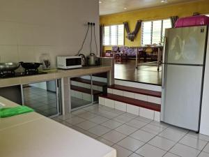 a kitchen with a white refrigerator and a table at THE CLOUD KINABALU- HOUSE in Ranau