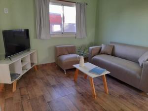 a living room with a couch and a tv and a table at La Narcisa in Pehuajo