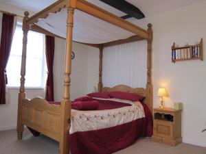 Schlafzimmer mit einem hölzernen Himmelbett und roten Kissen in der Unterkunft Black Swan Guest House in Marton