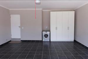 lavadero con armarios blancos y lavadora en MLMK Property 17, en Ciudad del Cabo 3 fotos más