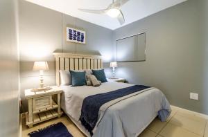 1 dormitorio con 1 cama grande con almohadas azules en Grace 10 Two Bedroom Beach Front Apartment, en East London
