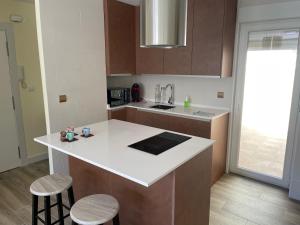 a kitchen with a white counter and two stools at Apartamento Turístico Ávila VUT in Avila