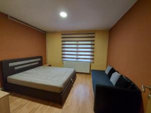 a bedroom with a bed and a couch and a window at Apartman Jovičić in Višegrad
