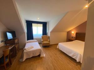 a hotel room with two beds and a television at Hotel Cristina in Noreña