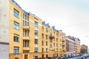 un edificio giallo su una strada con auto parcheggiate di WeHost 1BR Scandinavian Style Top Floor Apartment a Helsinki