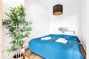 una camera con un letto blu e due piante in vaso di WeHost 1BR Scandinavian Style Top Floor Apartment a Helsinki