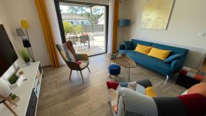 a living room with a blue couch and a table at Villa moderne avec spa à Montalivet in Vensac