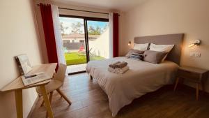 a bedroom with a bed and a desk and a window at Villa moderne avec spa à Montalivet in Vensac
