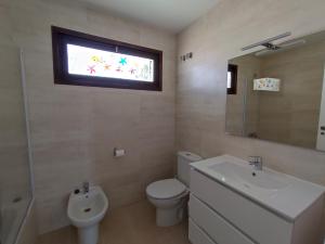 a bathroom with a toilet and a sink and a window at Benatorre Playa (Casa en primera línea de playa). in Torre de Benagalbón