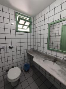 a bathroom with a toilet and a sink and a mirror at Hotel Porto Verde -JG in Porto Seguro