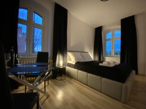 a bedroom with a bed and a table and windows at VIP Rooms Apartment in Toruń