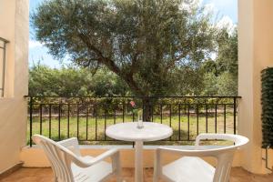 un tavolo bianco e sedie su un patio con un albero di Oliveland Apartments a Kávos