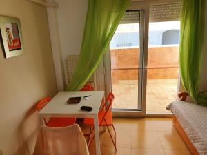 una pequeña mesa y sillas en una habitación con ventana en Apartamentos Vacacionales Atlanterra, en Zahara de los Atunes