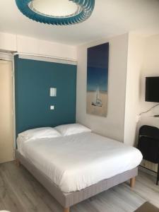 a bedroom with a white bed and a blue wall at Hôtel Aunis-Saintonge in Royan +16 photos