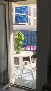 a table and chair on a balcony with a potted plant at Hôtel Aunis-Saintonge in Royan
