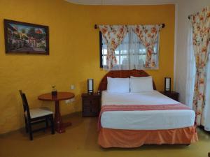 a bedroom with a bed, chair, table and window at Hotel El Moro in Puerto Morelos