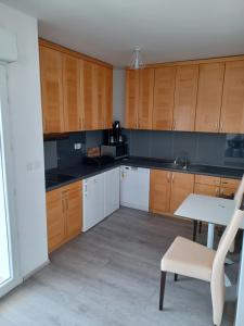 a kitchen with wooden cabinets and a table and a chair at APARTMANI JELIĆ in Stanići