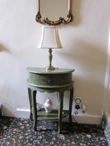a small green table with a lamp on it at Black Swan Guest House in Marton