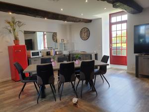 a dining room with a table and chairs and a kitchen at Chambres de Villée in Saint-Georges-de-Gréhaigne