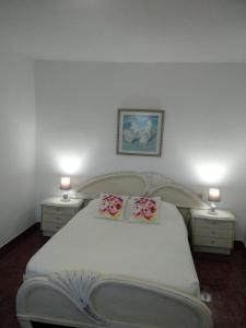 1 dormitorio con 1 cama blanca grande y 2 mesitas de noche en Apartamento puerto estaca 3, en Puerto de la Estaca