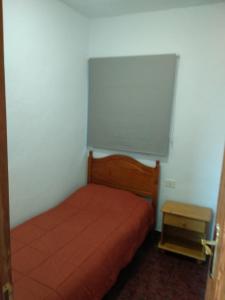 una piccola camera con letto rosso e tavolo di Apartamento puerto estaca 3 a Puerto de la Estaca