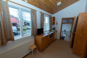 een kamer met een bureau, een televisie en ramen bij Kaffi Holar Cottages and Apartments in Sauðárkrókur